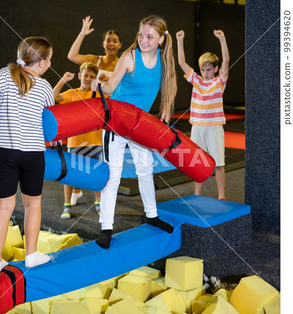 Children having funny wrestling by inflatable logs in indoor amusement park Children having funny wrestling by inflatable logs in indoor amusement park 99394620