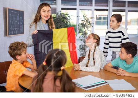 Teacher showing Belgium flag to group of schoolchildren 99394622