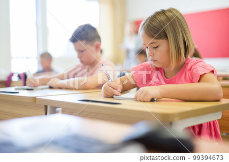 Diligent preteen schoolgirl making notes of teacher lecture Diligent preteen schoolgirl making notes of teacher lecture 99394673