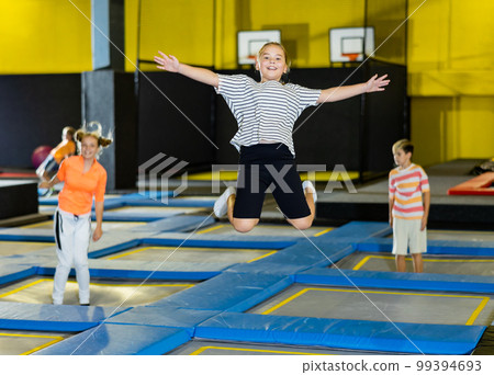 Tween girl having fun jumping in indoor trampoline arena 99394693