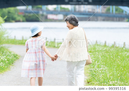 girl and grandma walking hand in hand 99395316