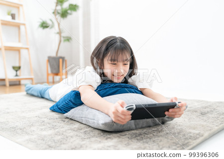 girl lying down and playing games 99396306