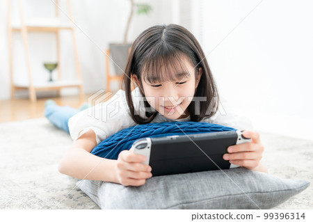girl lying down and playing games 99396314