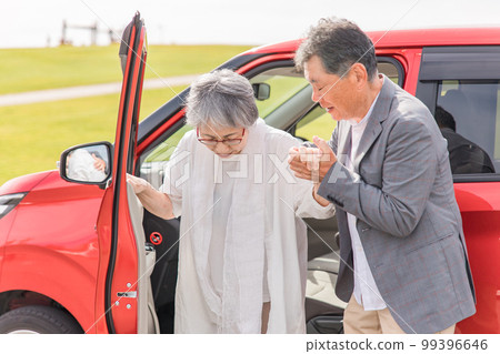 An elderly woman getting off a car and a man helping (transfer) An elderly woman getting off a car and a man helping (transfer) 99396646