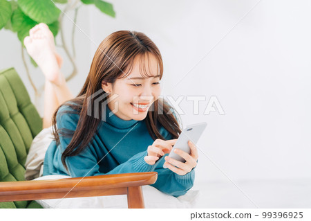 躺在沙發上使用智能手機的女人 99396925