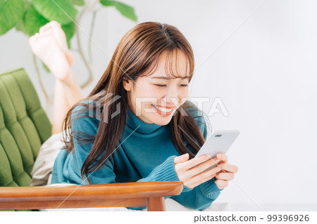 躺在沙發上使用智能手機的女人 99396926