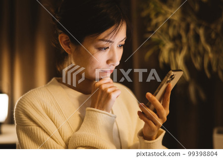 A woman looking at a smartphone at night, an anxious woman, a troubled woman 99398804