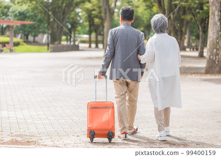Rear view of an elderly couple traveling with a suitcase 99400159