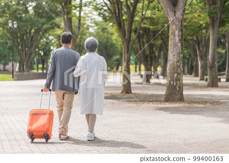 Rear view of an elderly couple traveling with a suitcase 99400163
