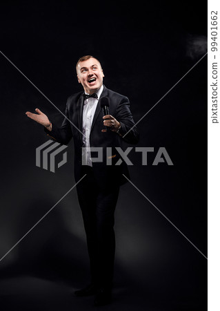 Full length of young man in costume with microphone on black background, singer, actor, leading  99401662