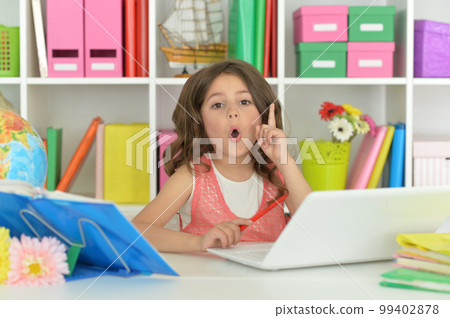Little girl ding home work at desk Little girl ding home work at desk 99402878
