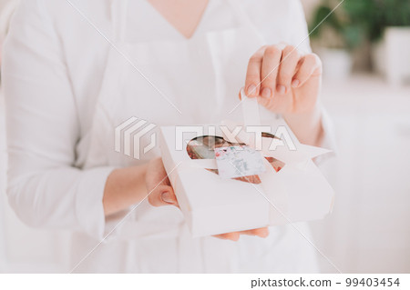 Girl in a white uniform holding chocolate-covered strawberries in a gift box Girl in a white uniform holding chocolate-covered strawberries in a gift box 99403454