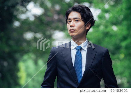 A businessman in a suit walking on a green road 99403601