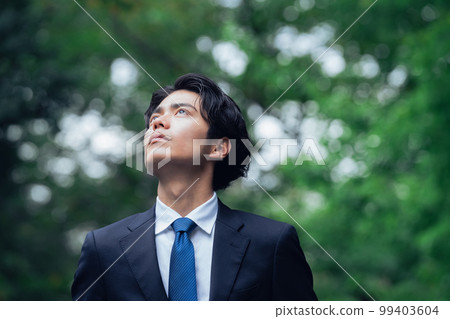 A businessman in a suit walking on a green road 99403604
