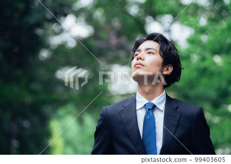 A businessman in a suit walking on a green road 99403605