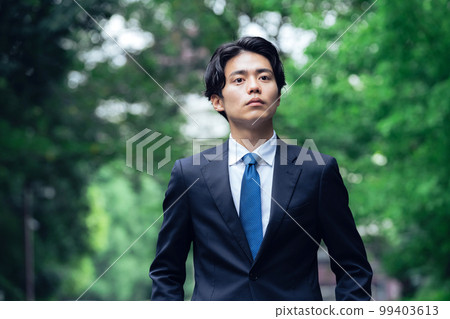 A businessman in a suit walking on a green road A businessman in a suit walking on a green road 99403613