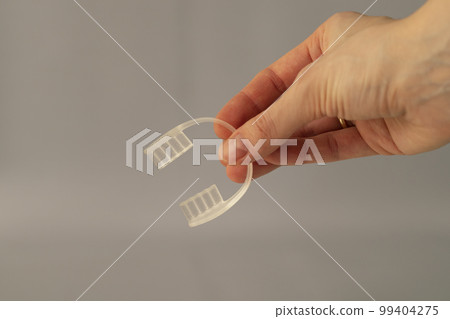 Nighttime dental care. Keeping teeth healthy overnight. Mouth guard in a woman's hand on a beige background 99404275