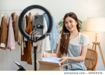Female online seller is using smartphone to broadcast live on Vlog for introduce fashions and selling Female online seller is using smartphone to broadcast live on Vlog for introduce fashions and selling 99404436