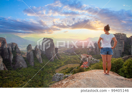 Young woman in white t-shirt standing in front of Greece Meteora mountains, monastery and village Young woman in white t-shirt standing in front of Greece Meteora mountains, monastery and village 99405146