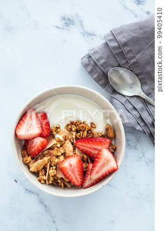 Homemade green buckwheat and nuts granola with coconut yogurt and strawberries in breakfast bowl. Healthy alternative food concept. Homemade green buckwheat and nuts granola with coconut yogurt and strawberries in breakfast bowl. Healthy alternative food concept. 99405410