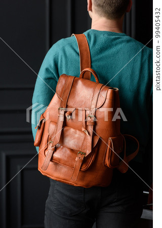 Orange leather oldfashioned backpack on a mans back Orange leather oldfashioned backpack on a mans back 99405432