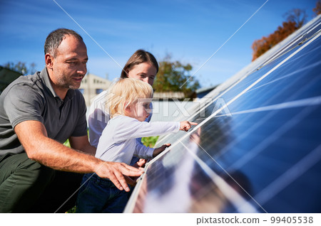 Enthusiastic father showing potential of alternative energy. Contemporary family looking at new solar station they bought. Side view of happy parents and interested child next to solar panels. 99405538