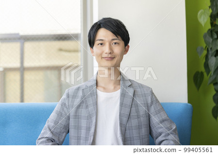 Portrait of a man in his twenties smiling looking at the camera 99405561