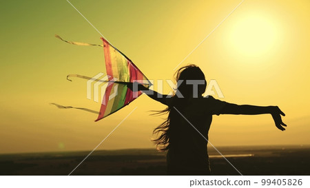 child launches kite sunset. silhouette teenage girl playing with wind sunset. happy family. childhood dream fly. flying a kite sky sunset. happy family concept. colored children toy with wind 99405826