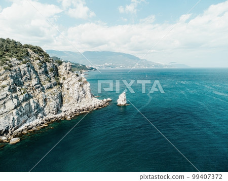 aerial photo of rock Parus Sail and Ayu-Dag Bear Mountain and near Gaspra, Yalta, Crimea at bright sunny day over the Black sea. Rock Parus in Gaspra near Swallow's nest in Crimea. aerial photo of rock Parus Sail and Ayu-Dag Bear Mountain and near Gaspra, Yalta, Crimea at bright sunny day over the Black sea. Rock Parus in Gaspra near Swallow's nest in Crimea. 99407372