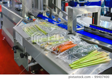 Fresh vegetables packed in a clear plastic bag production line in factory, industrial food production Fresh vegetables packed in a clear plastic bag production line in factory, industrial food production 99407400