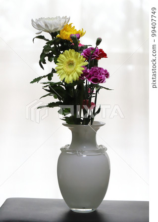 Chrysanthemum, carnation and gerbera flowers in a white vase indoors Chrysanthemum, carnation and gerbera flowers in a white vase indoors 99407749