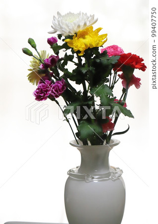Chrysanthemum, carnation and gerbera flowers in a white vase indoors Chrysanthemum, carnation and gerbera flowers in a white vase indoors 99407750