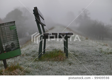 Parkbench and a dustbin on a dike as a closeup 99409598