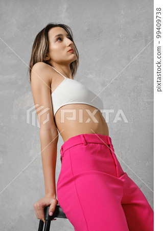 Dreamy woman in rests her hands on the seat of tall stool 99409738