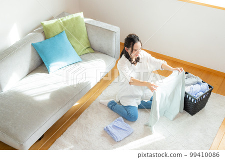A woman folding laundry 99410086