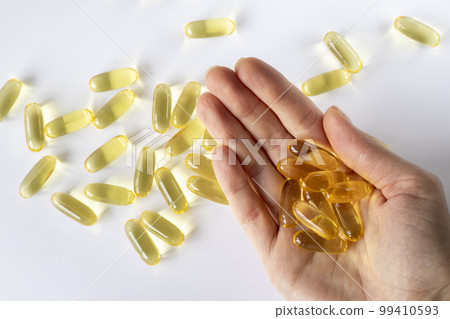 Fish oil in a woman's hand on a white background with scattered capsules. Fish oil in a woman's hand on a white background with scattered capsules. 99410593