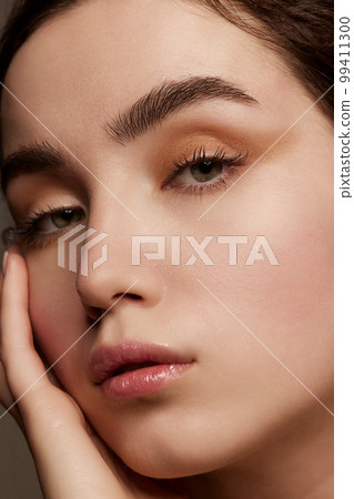 Close-up portrait of young beautiful girl with shimmer eye shadow makeup. Well-kept healthy skin condition. Concept of natural beauty, skin care, cosmetology 99411300