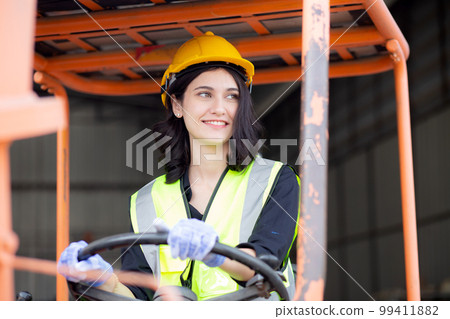 Young asian woman is foreman driving forklift at distribution warehouse, engineer working. 99411882