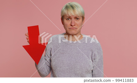 Upset young woman showing red arrow pointing down, concept of downgrade bankruptcy money fail, fall Upset young woman showing red arrow pointing down, concept of downgrade bankruptcy money fail, fall 99411883