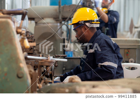 Young black engineer man operating lathe machine for preparing production at factory. Young black engineer man operating lathe machine for preparing production at factory. 99411885