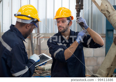 Two engineer man working with machine robot automatic together at factory. 99411886