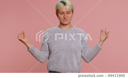 Woman breathes deeply with mudra gesture, eyes closed, meditating with concentrated thoughts alone 99411900