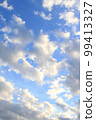 Blue sky with clouds. White and pink clouds on a blue sky background. Landscape at sunset or sunrise. A clear sunny day. Light natural neutral background, wallpaper, postcard, banner. Nature photo 99413327