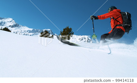 Freeride skier riding in the scenic mountains with blue sky 99414118