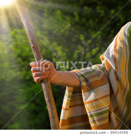 Man's hand with a wooden staff 99414348