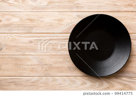 Top view of black plate on wooden background. Empty space for your design Top view of black plate on wooden background. Empty space for your design 99414775