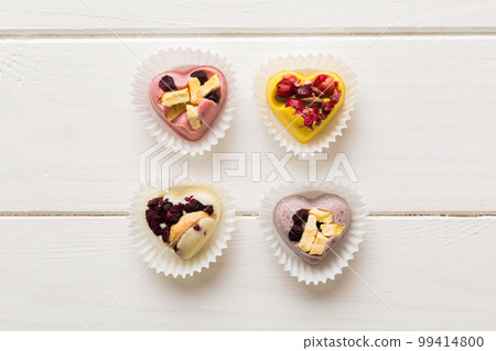 chocolate sweets in the form of a heart with fruits and nuts on a colored background. top view with space for text, holiday concept 99414800