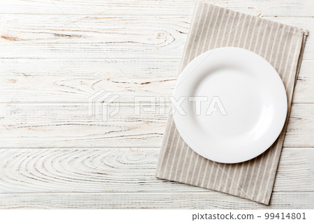 Top view on colored background empty round white plate on tablecloth for food. Empty dish on napkin with space for your design Top view on colored background empty round white plate on tablecloth for food. Empty dish on napkin with space for your design 99414801