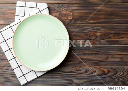 Top view on colored background empty round green plate on tablecloth for food. Empty dish on napkin with space for your design Top view on colored background empty round green plate on tablecloth for food. Empty dish on napkin with space for your design 99414804