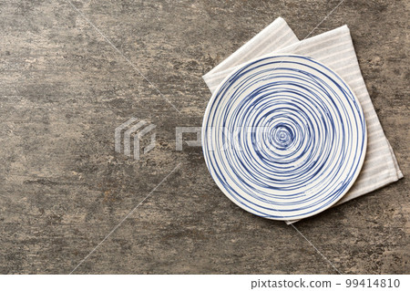 Top view on colored background empty round blue plate on tablecloth for food. Empty dish on napkin with space for your design Top view on colored background empty round blue plate on tablecloth for food. Empty dish on napkin with space for your design 99414810